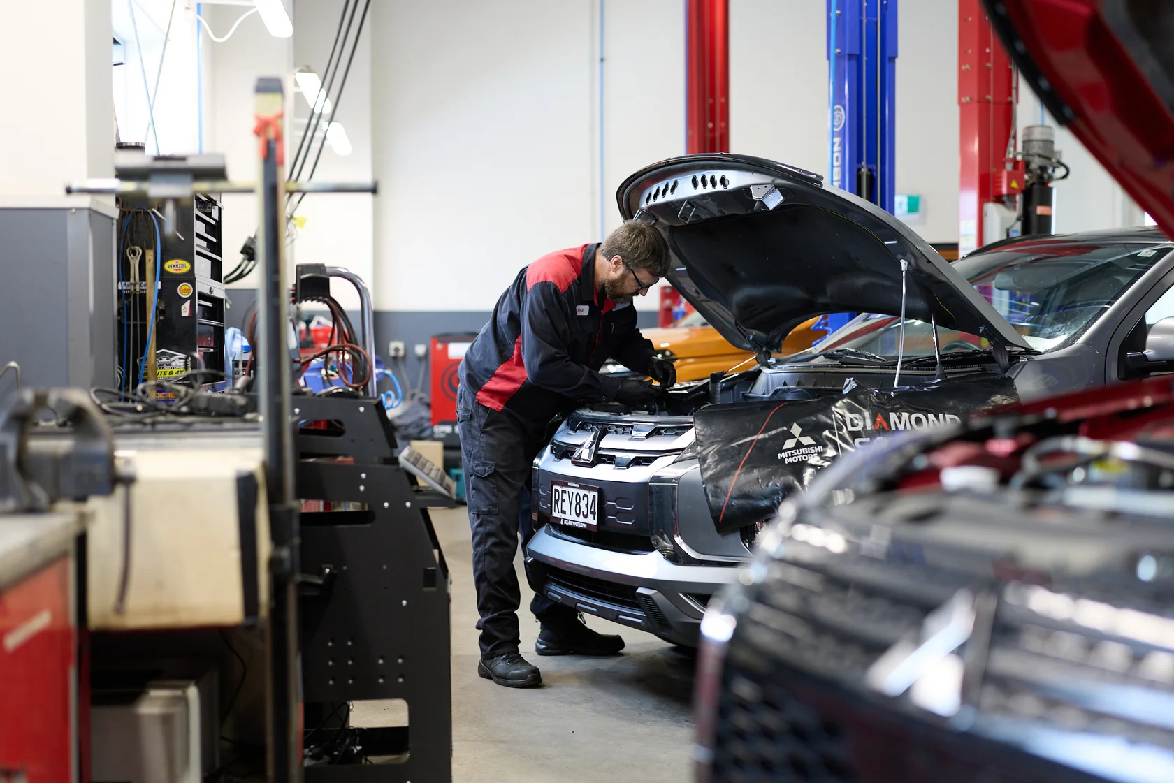 Mitsubishi dealer technician working under the bonnet of a vehicle